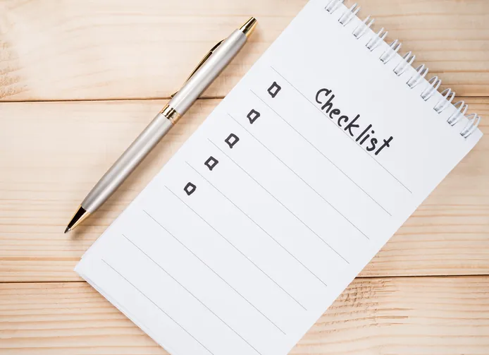 Checklist on notebook page with pen on wood background