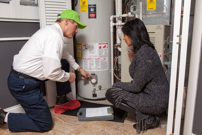 ABC plumbing technician showing homeowner a water heater