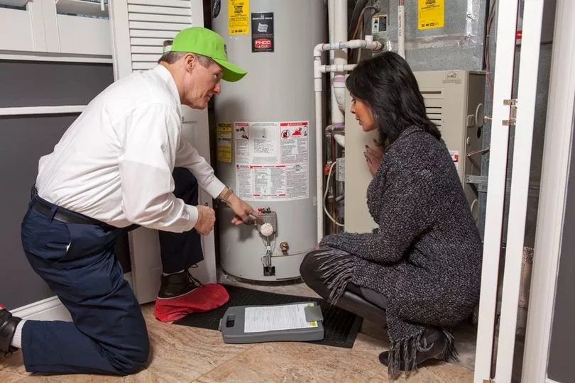 ABC plumbing technician showing homeowner a water heater