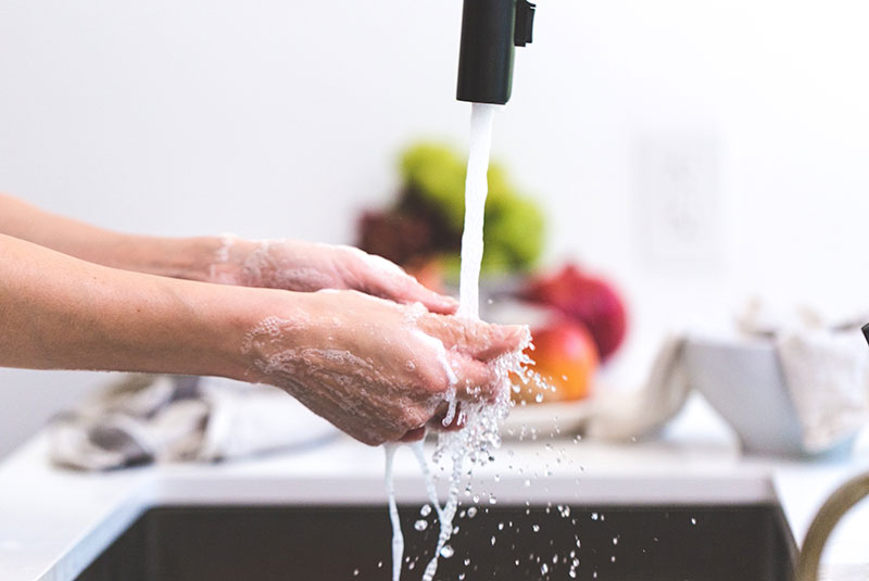 person washing hands in sink