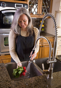 A woman washing radishes in the kitchen sink