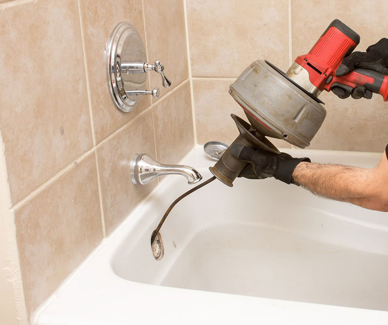 Closeup of an expert plumber snaking a bathtub drain