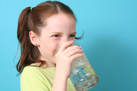 Young girl in pigtails drinking a glass of water