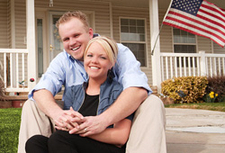 Man and woman sitting together on sidewalk in front of a home