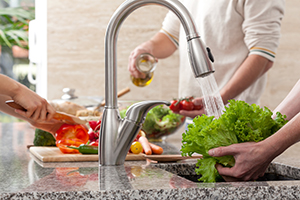 people washing vegetables in sink and cutting in kitchen