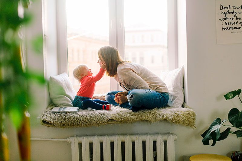 baby's hand son mothers face sitting on window seat