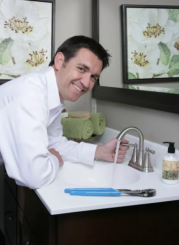 plumber smiling while inspecting bathroom sink