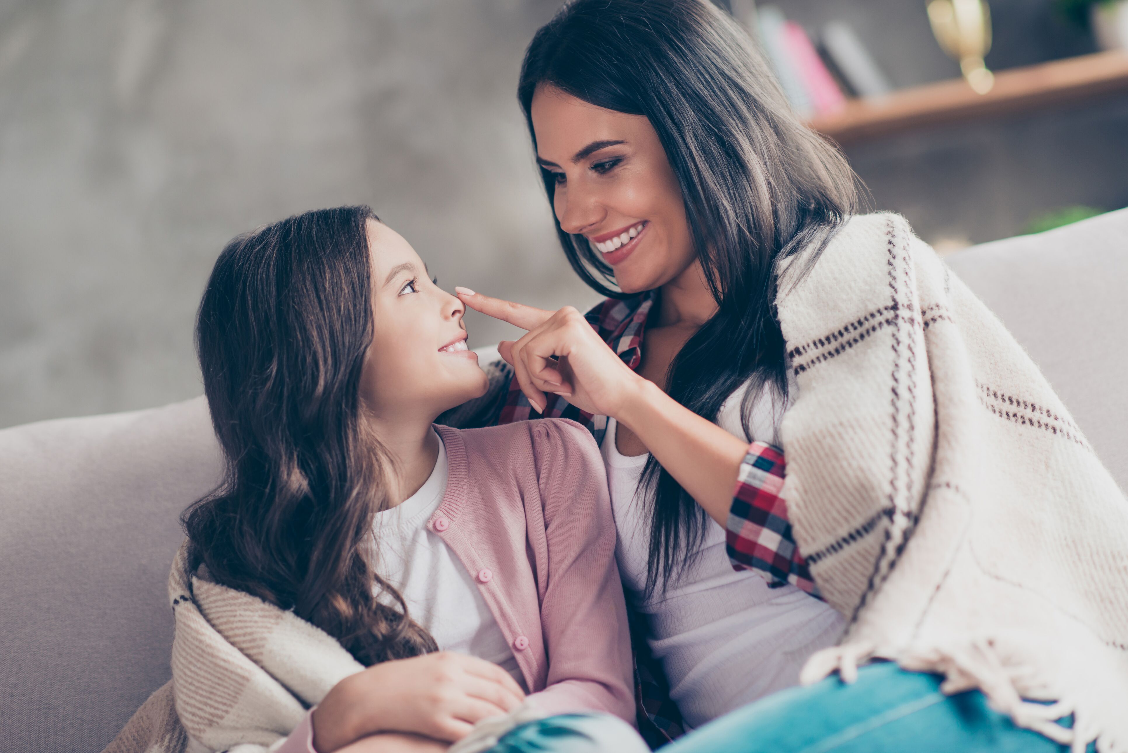 A woman playfully touching her daughter's nose