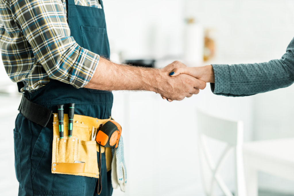 cropped image of Sarasota plumber and client shaking hands in kitchen