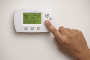 Closeup of hand on digital thermostat set at 78 degrees