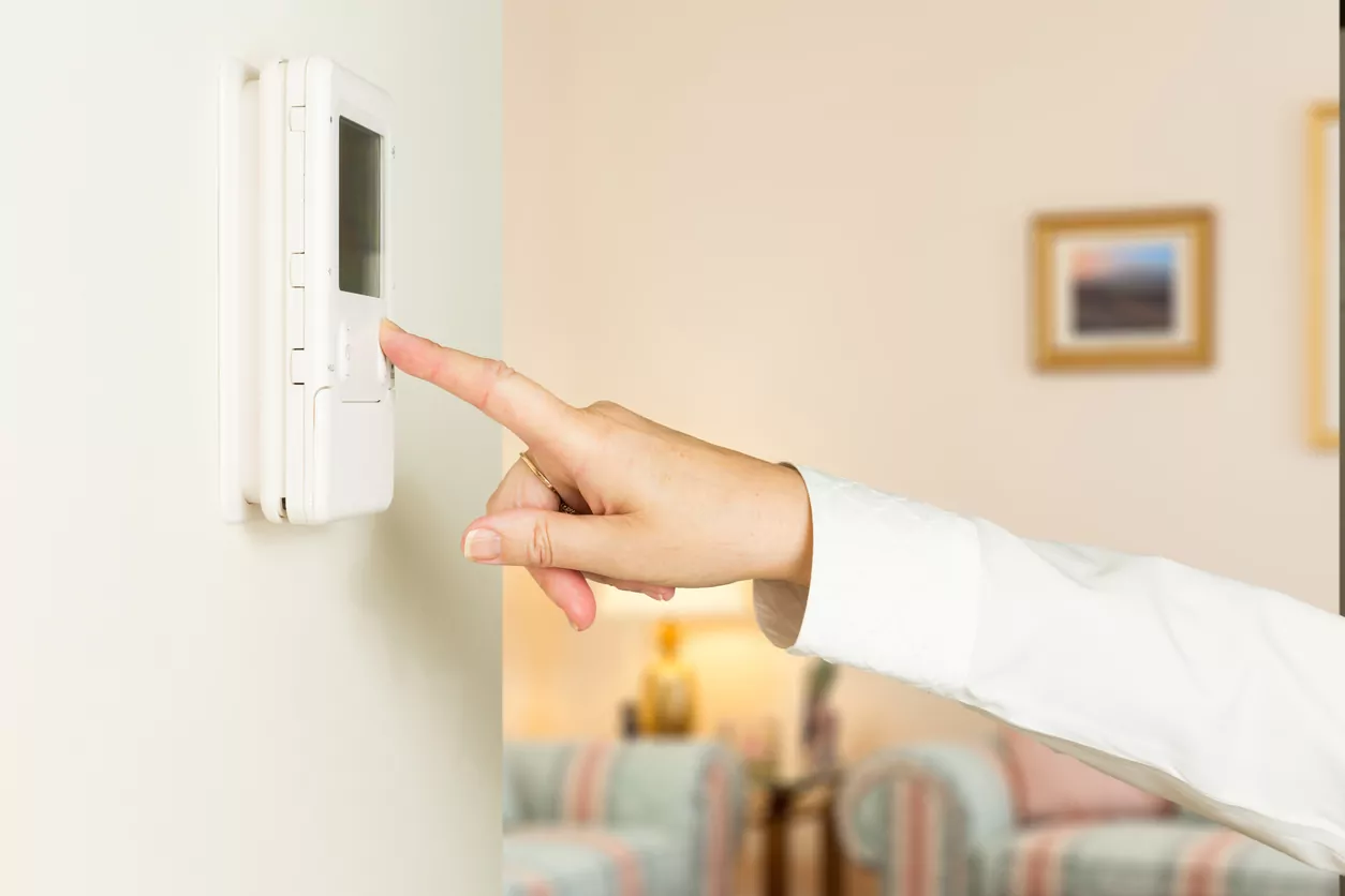 closeup of a hand pressing a modern thermostat