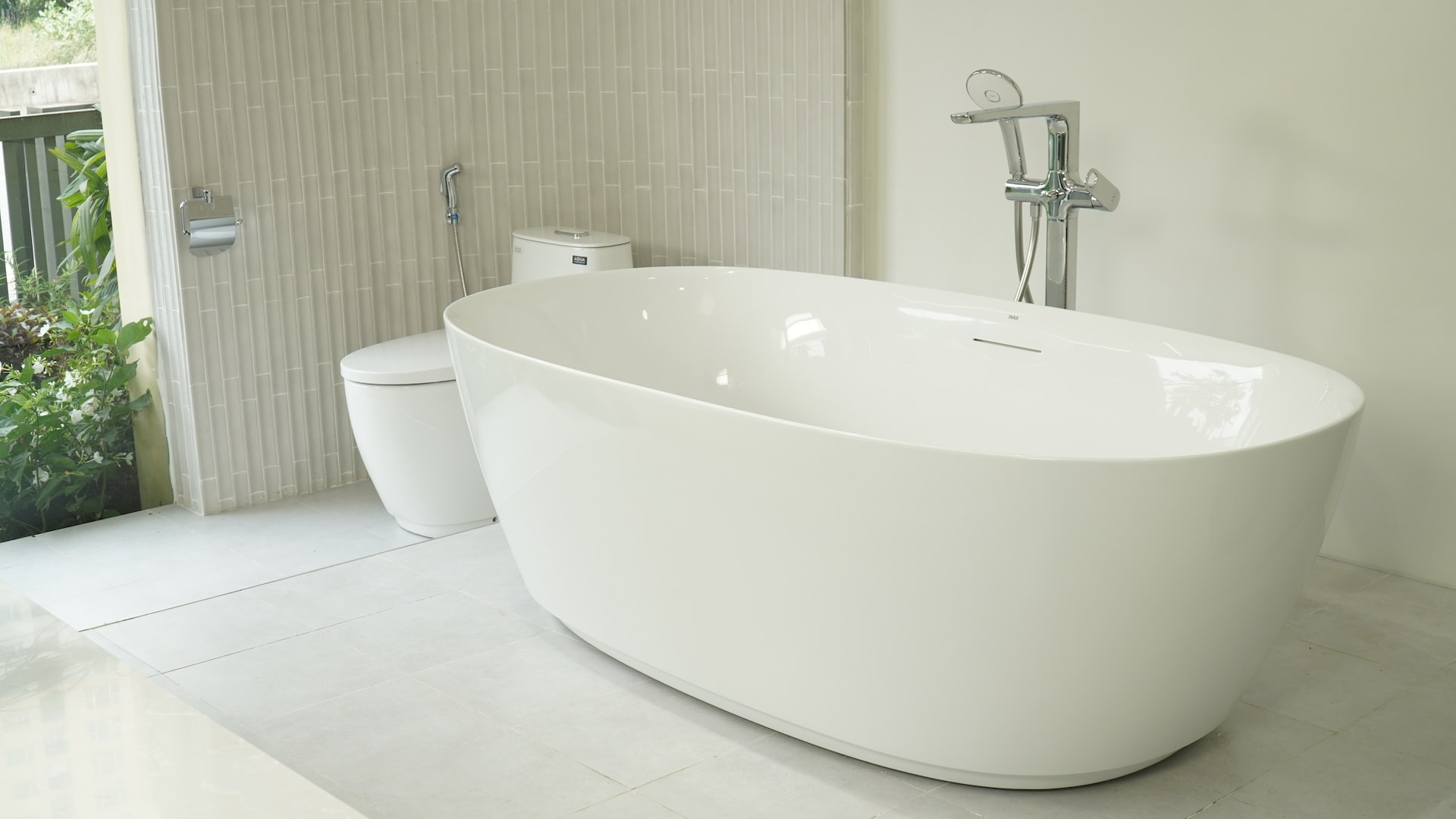 upgraded standalone bathtub next to toilet in white bathroom