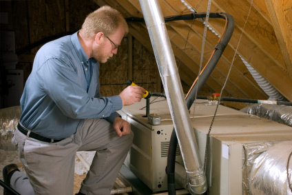 HVAC technician working on an air handler in an attic